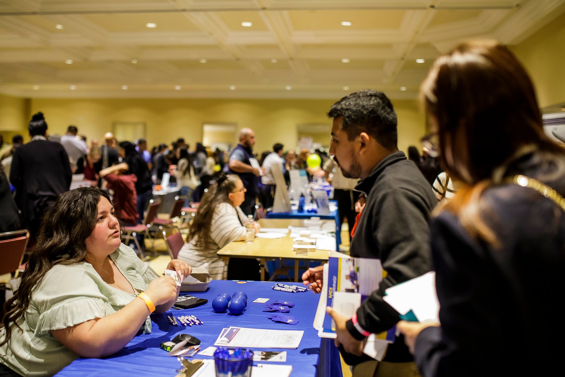Person speaking to someone at a booth at a job fair. Person speaking to someone at a booth at a job fair.