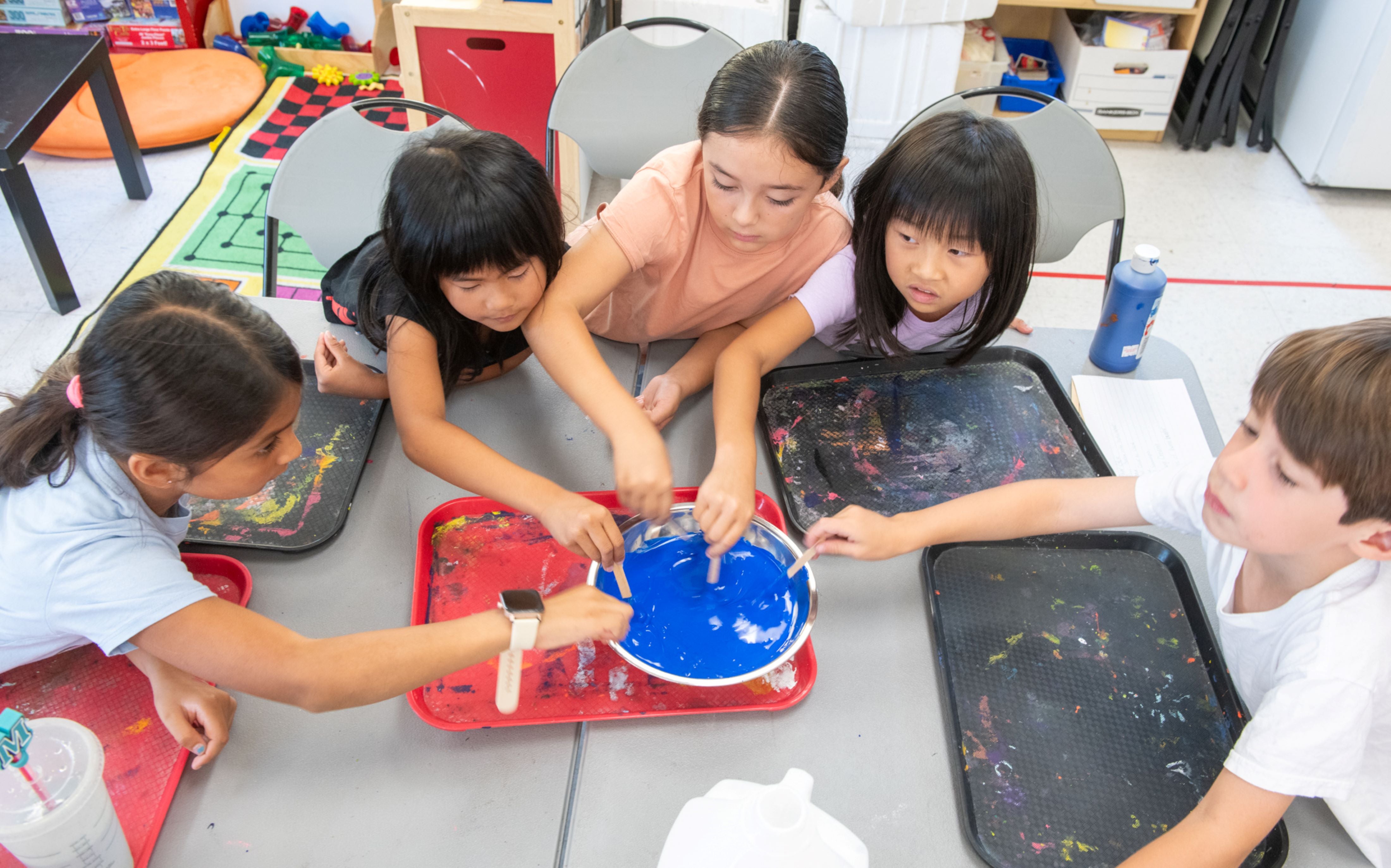 A group of kids mixing blue paint A group of kids mixing blue paint