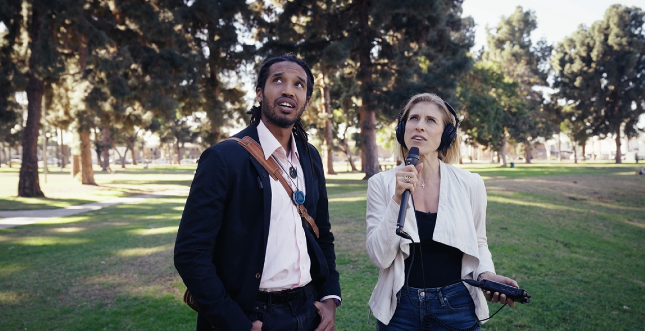 Two people standing in the park with AV equipment Two people standing in the park with AV equipment