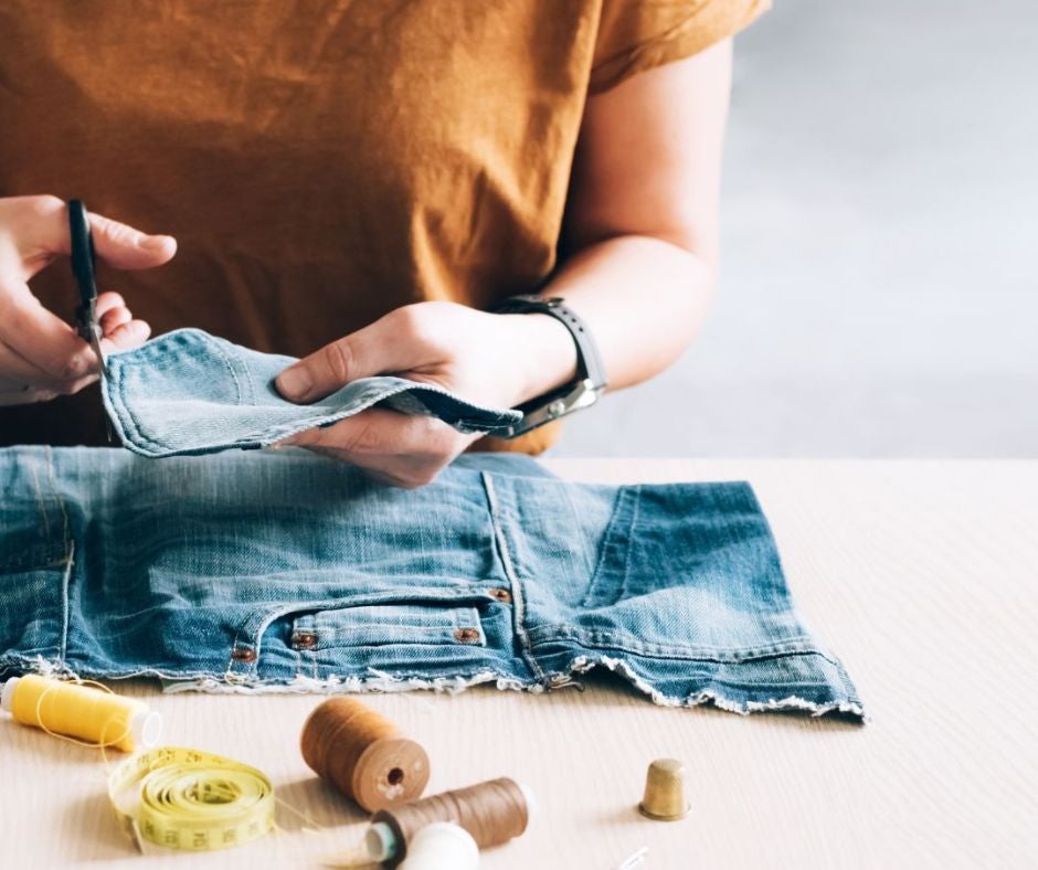 A woman cuts jeans with scissors A woman cuts jeans with scissors