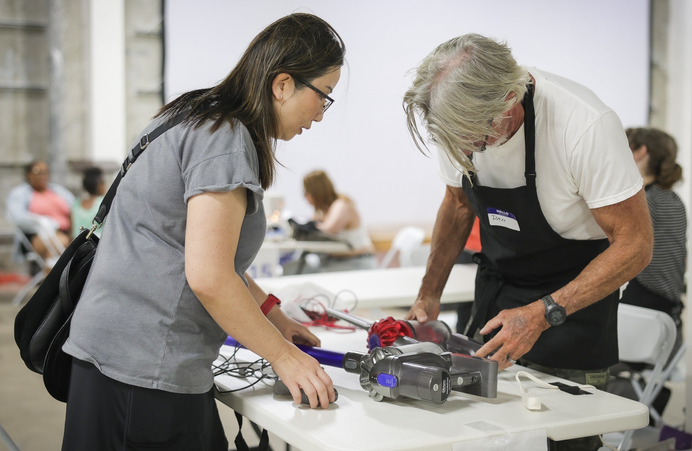 Woman and man working on a vacuum cleaner. Woman and man working on a vacuum cleaner.