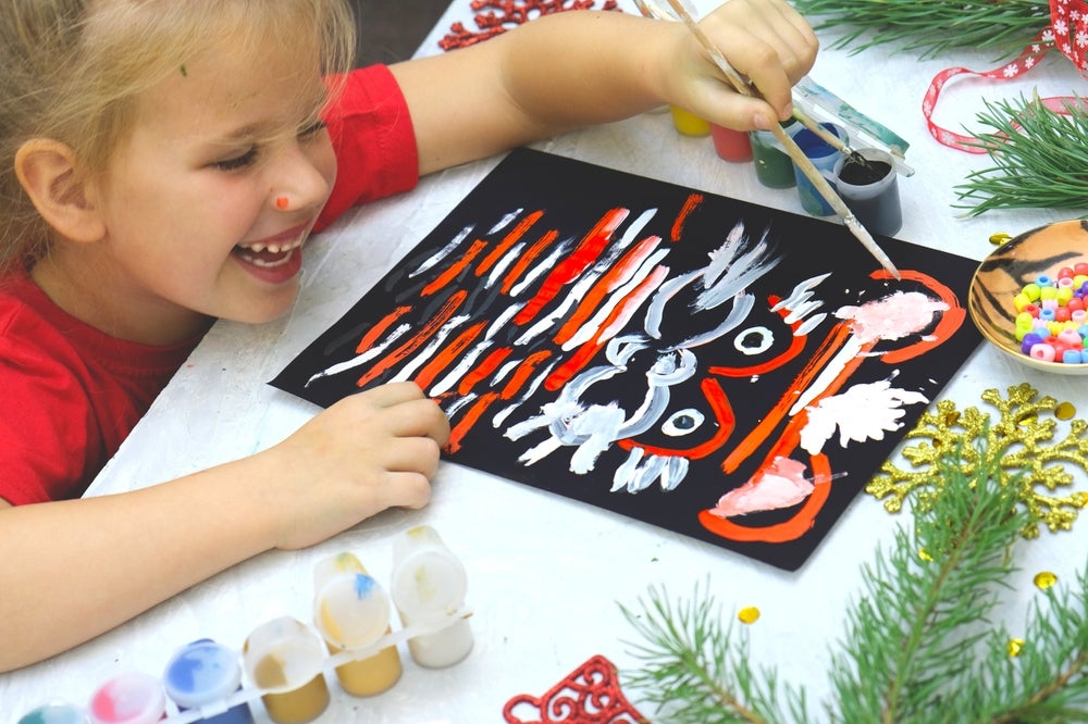 A little girl paints a holiday picture. 