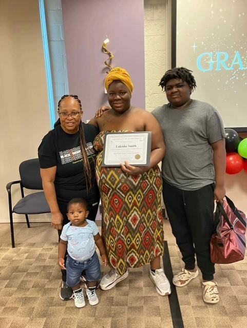 A group of people together, one woman holds a certificate 