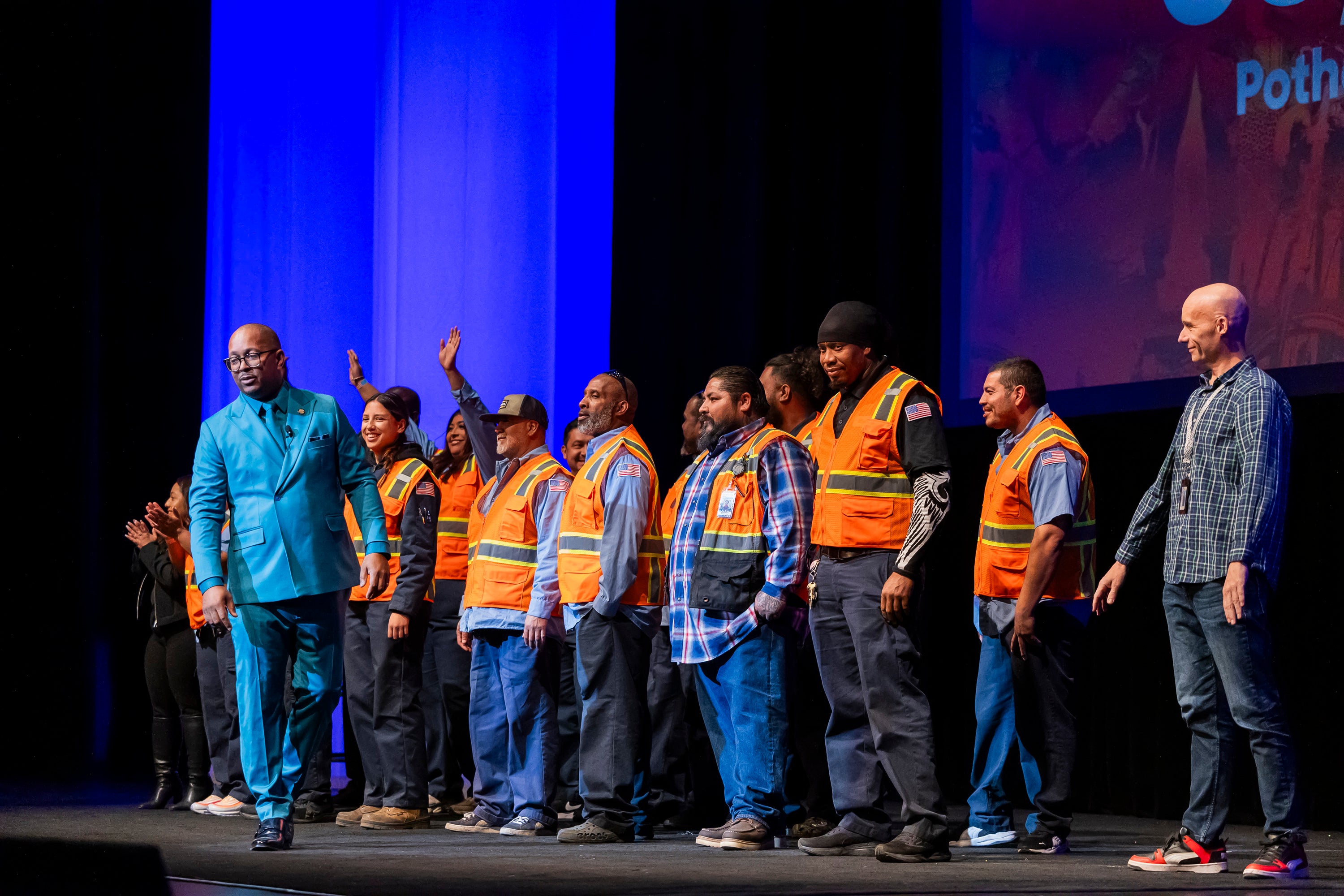 A man in a green suit with people in safety vests A man in a green suit with people in safety vests