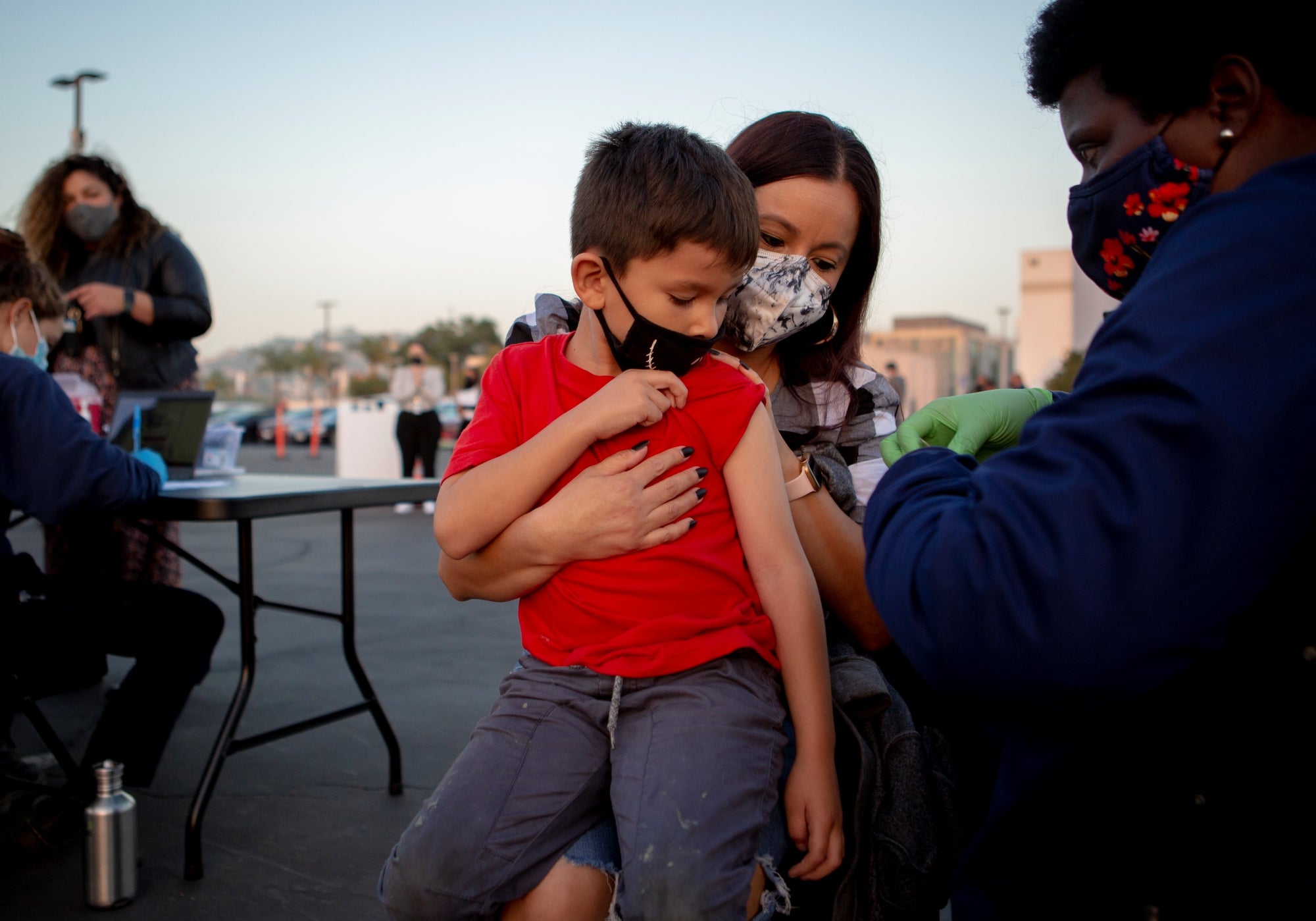 A little boy sitting on his mom's lap gets a vaccine. A little boy sitting on his mom's lap gets a vaccine.