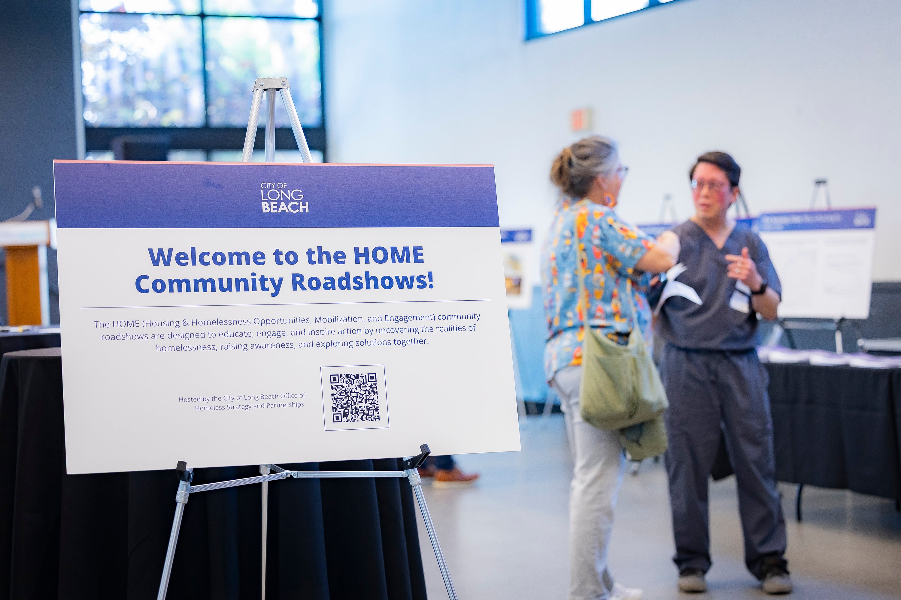 Two women standing next to a sign. Two women standing next to a sign.