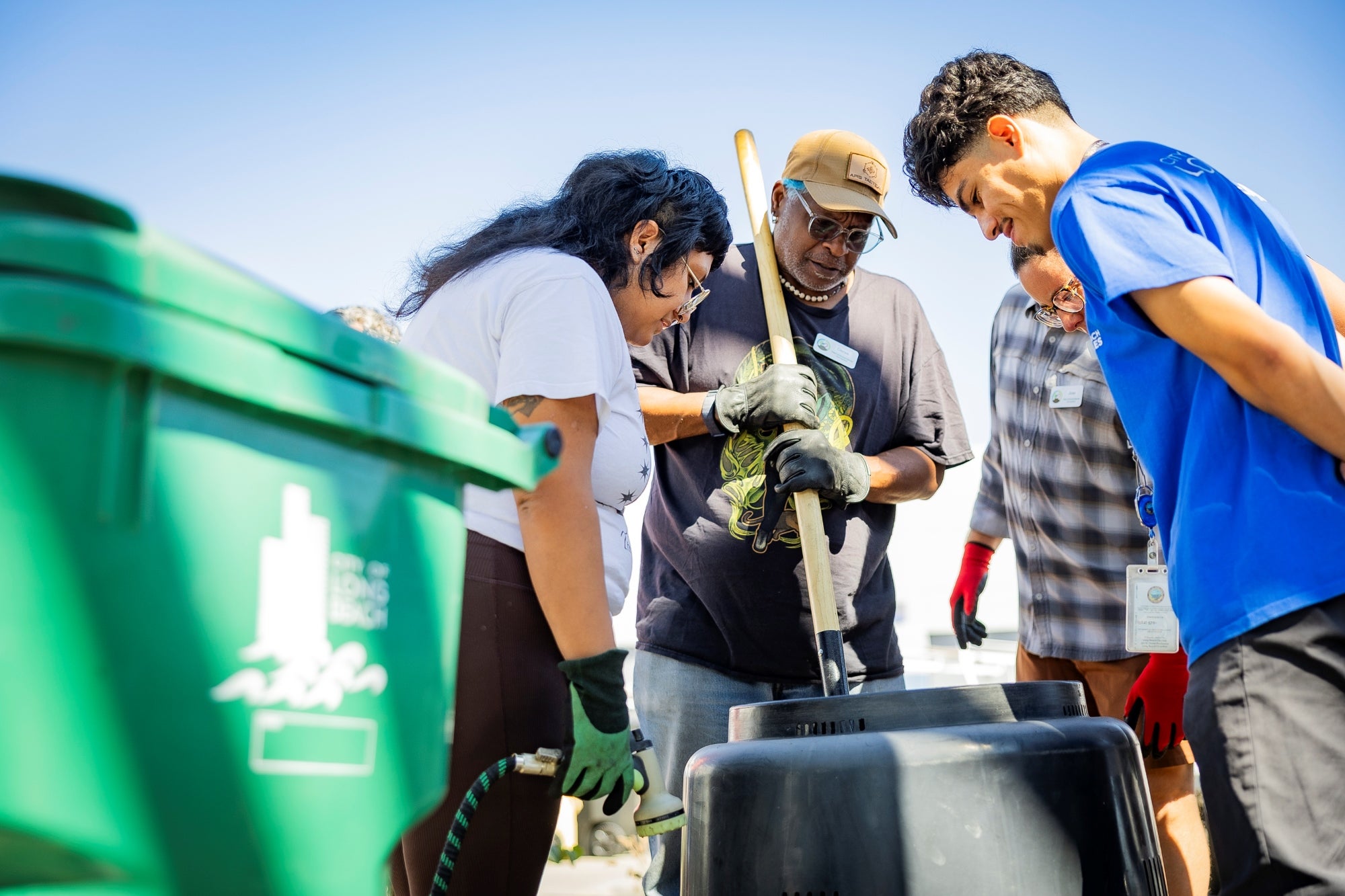 A group of people standing over a black bin. A group of people standing over a black bin.