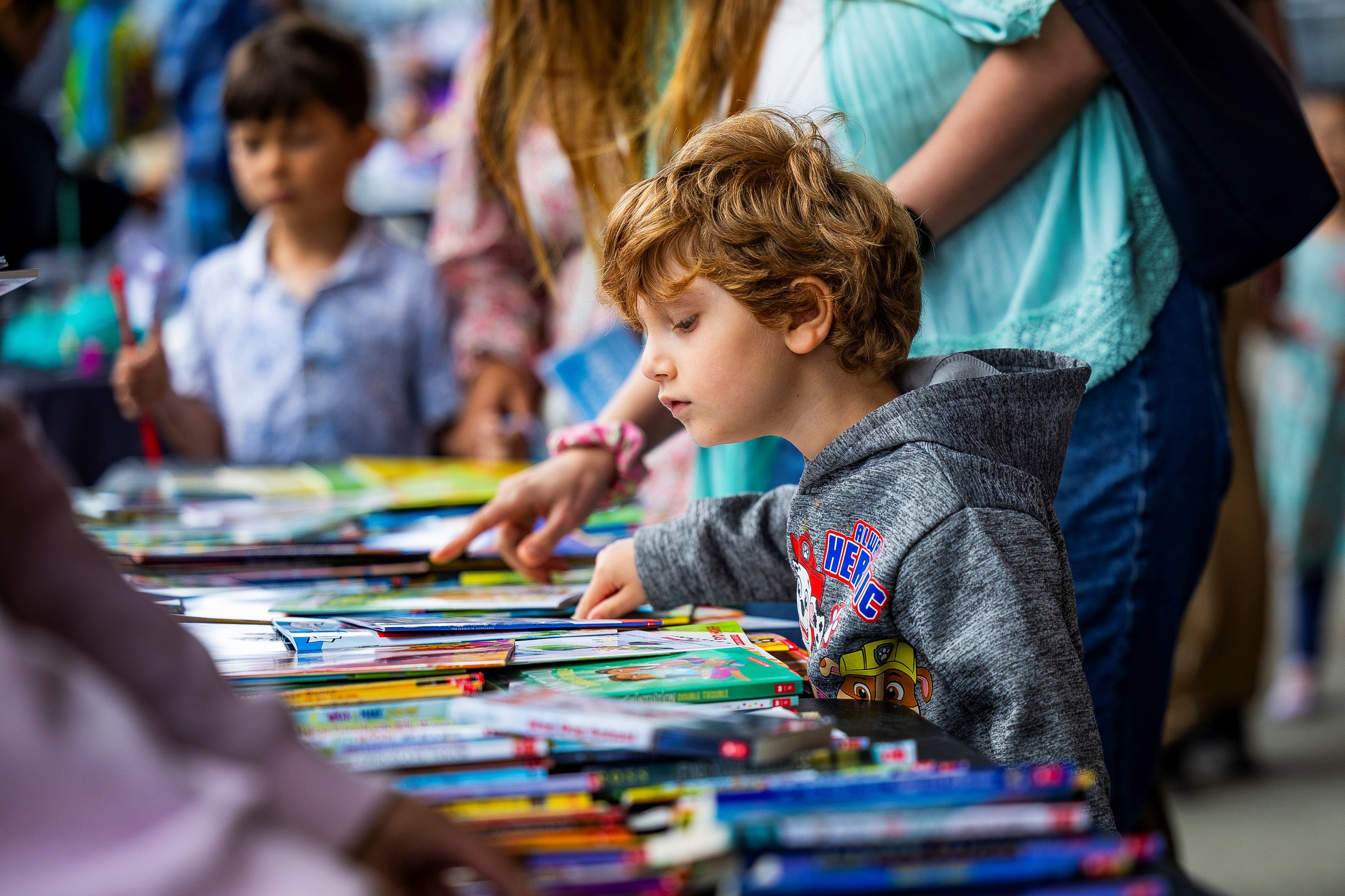 A child looking at books on a table A child looking at books on a table