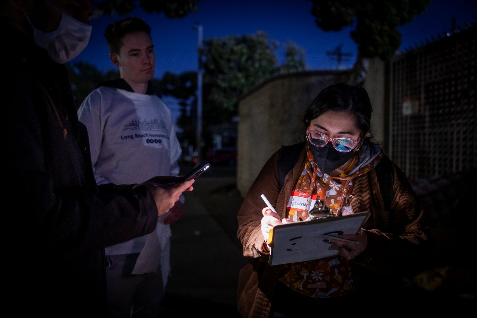 Masked woman writes on clipboard 