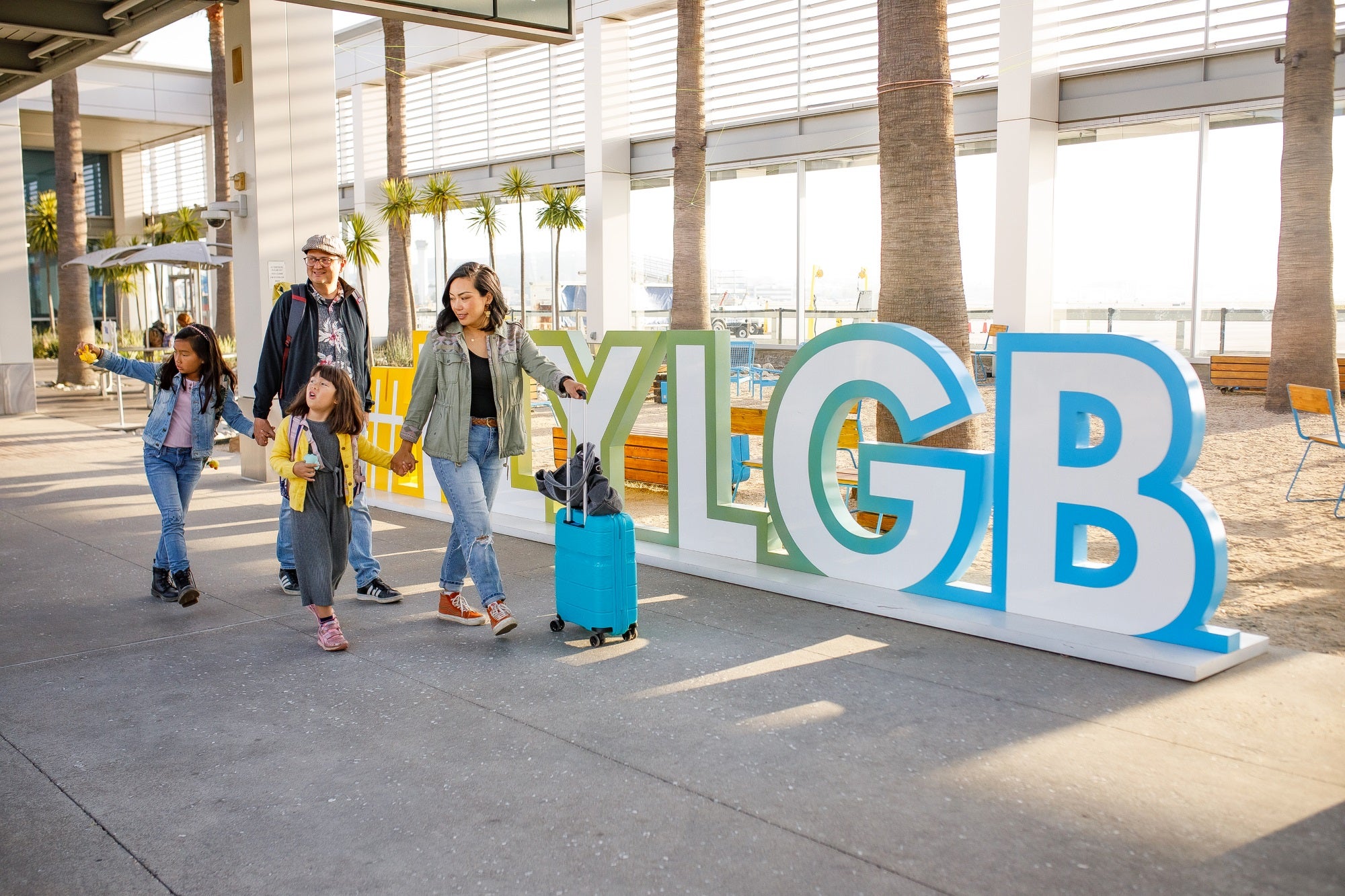 Family walks in front of LGB Airport signage.  Family walks in front of LGB Airport signage.