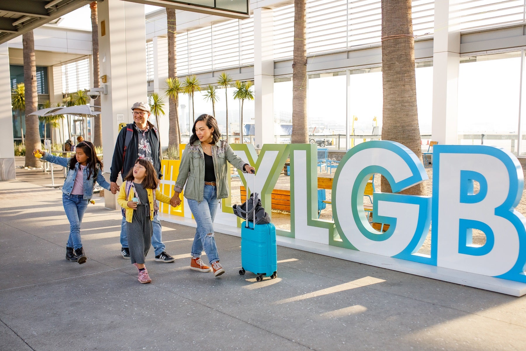 Family walks in front of LGB Airport signage. Family walks in front of LGB Airport signage.