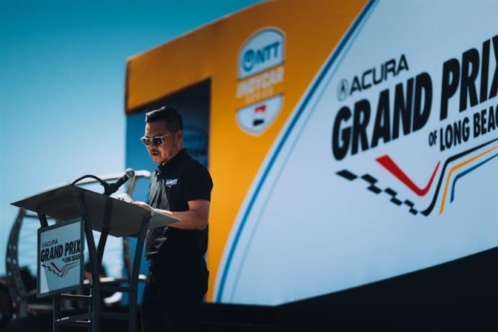 A man speaks at a podium with a colorful banner behind him A man speaks at a podium with a colorful banner behind him