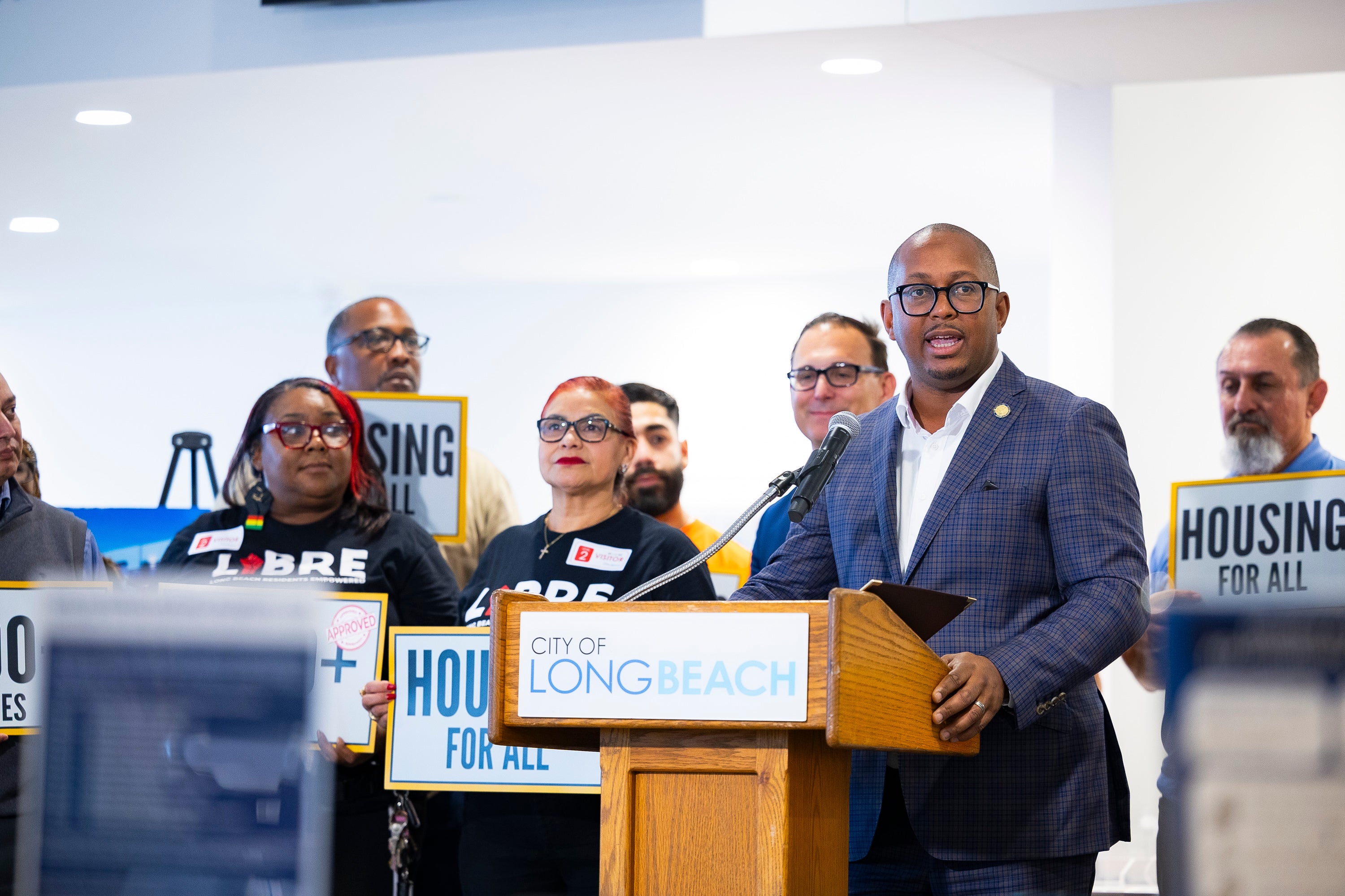 Mayor stands at podium with group of people behind him 