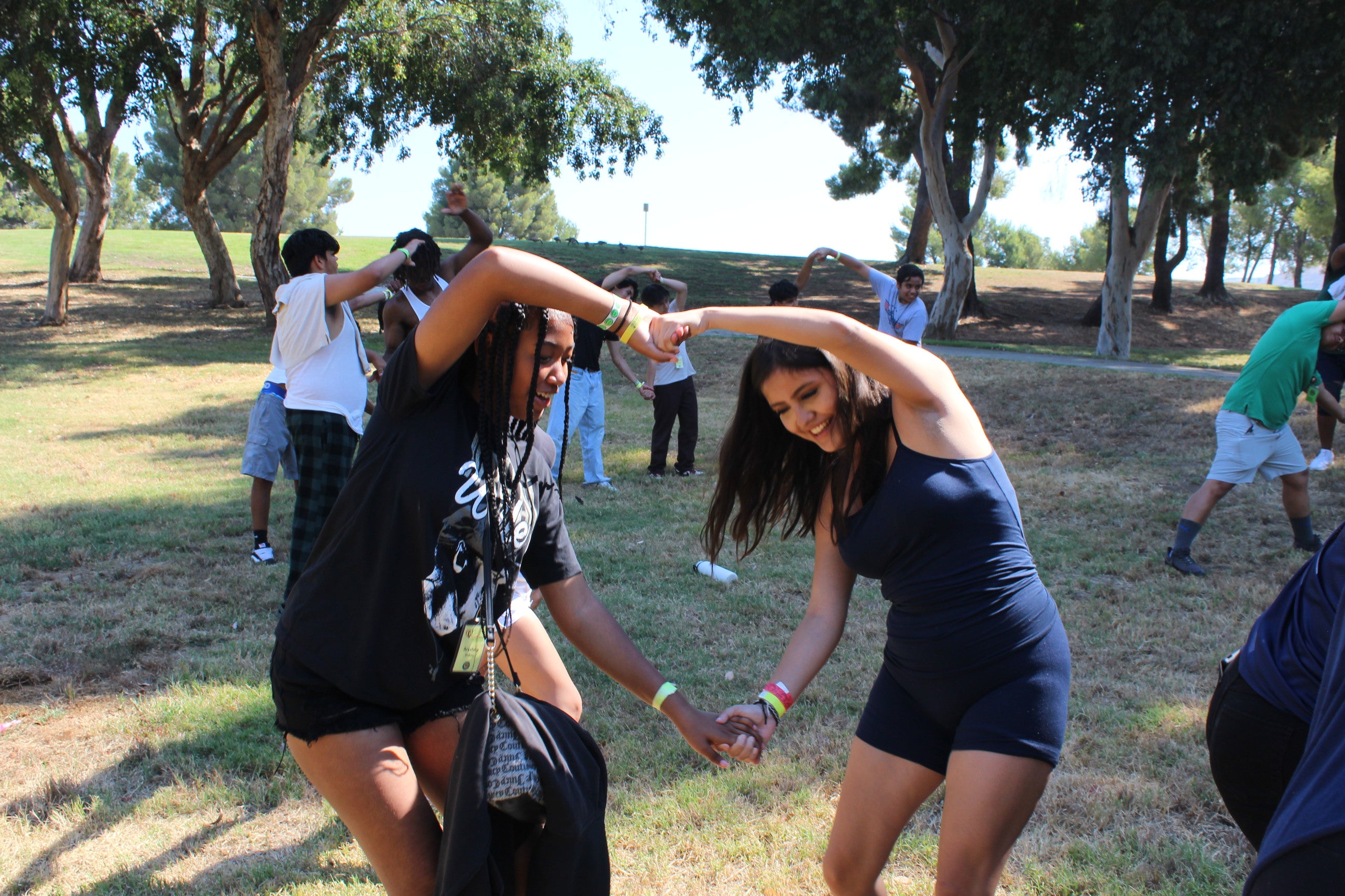 Two girls in black clothing participating in a pair exercise on a field of grass. Two girls in black clothing participating in a pair exercise on a field of grass.