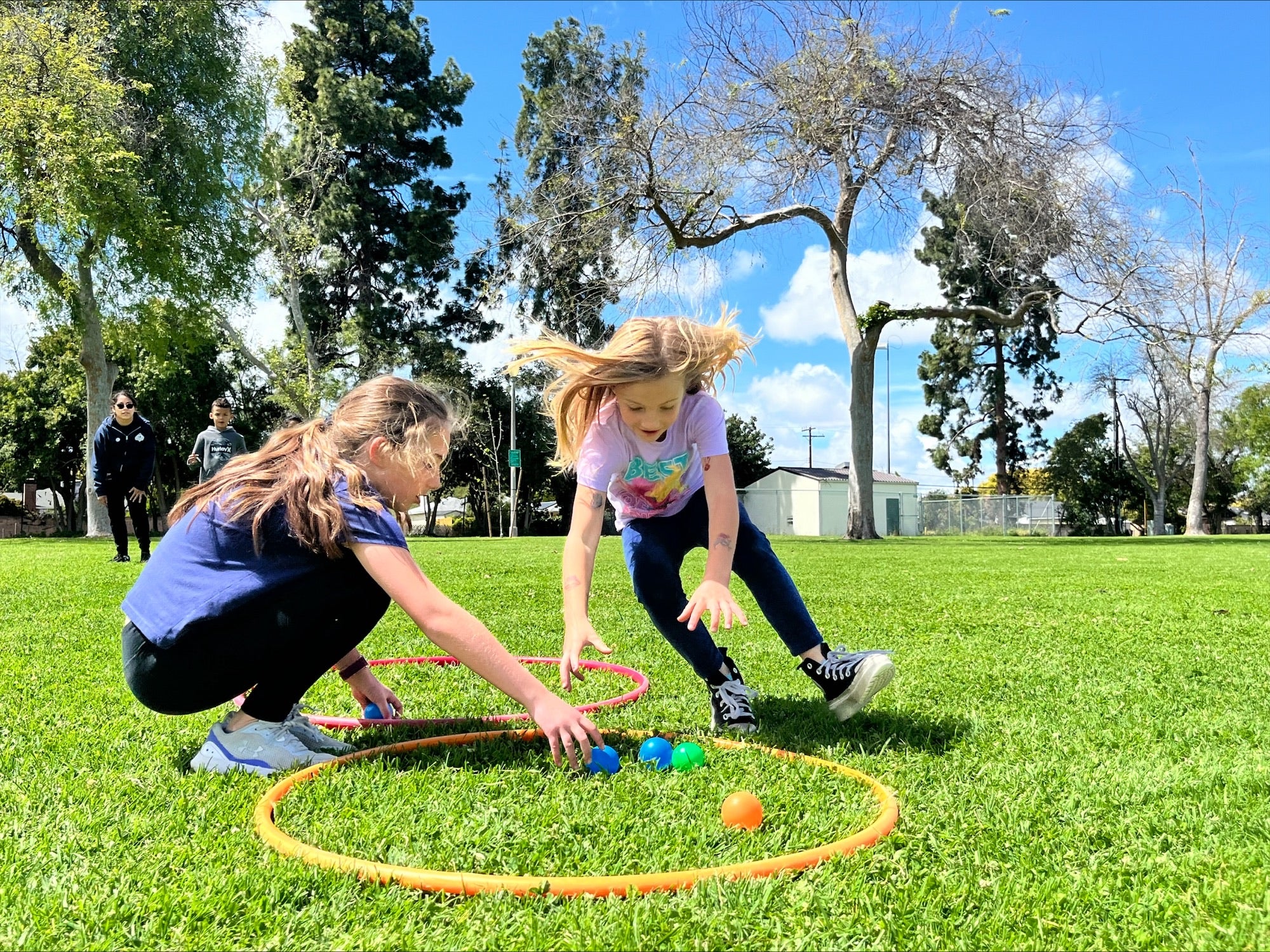 Two girls collect balls in a park. Two girls collect balls in a park.