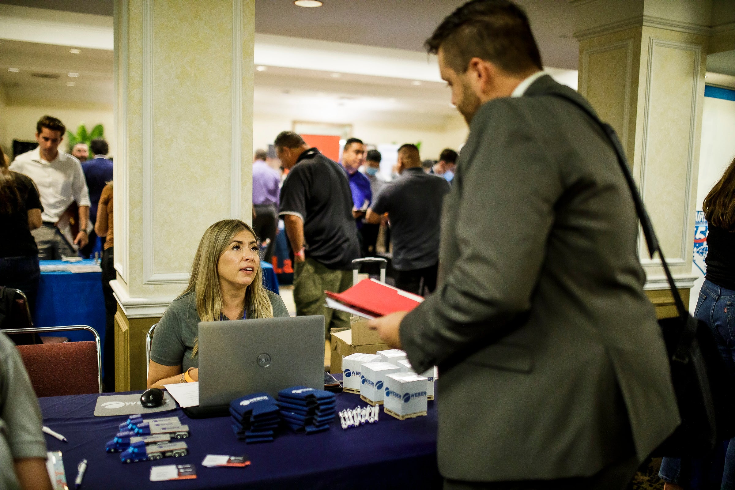 A man in a suit speaks with a woman at a table A man in a suit speaks with a woman at a table